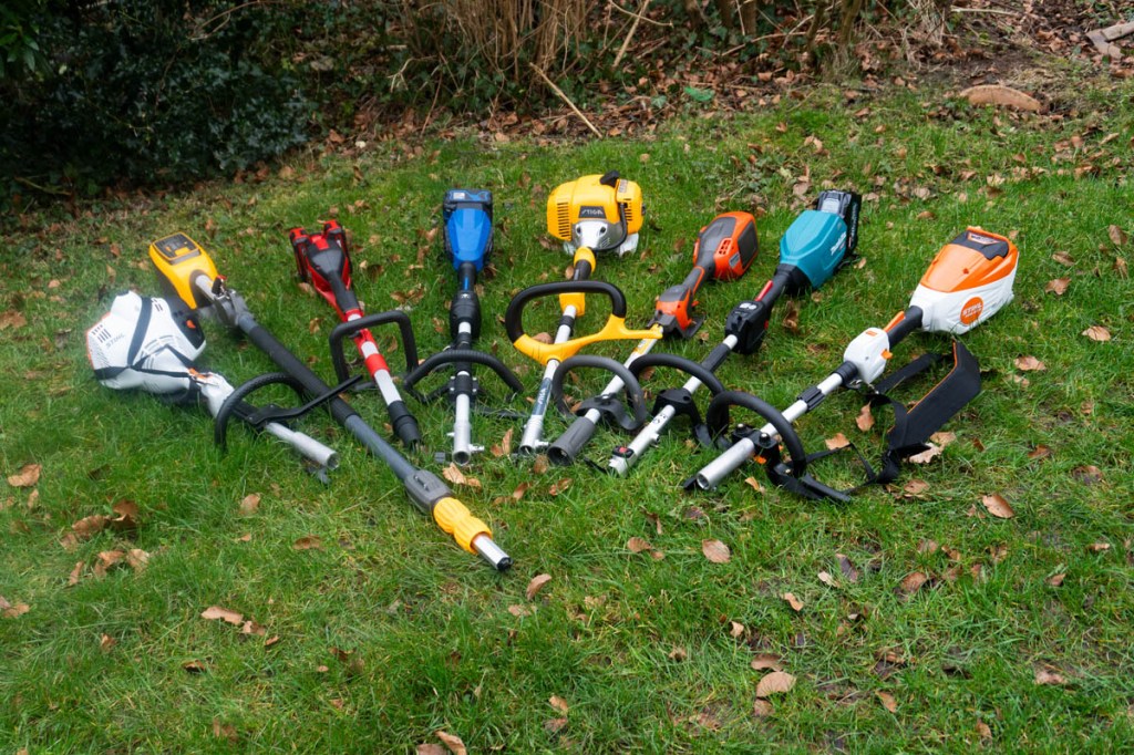 Antriebsköpfe aller acht Kombigeräte im Test auf einer Wiese liegend